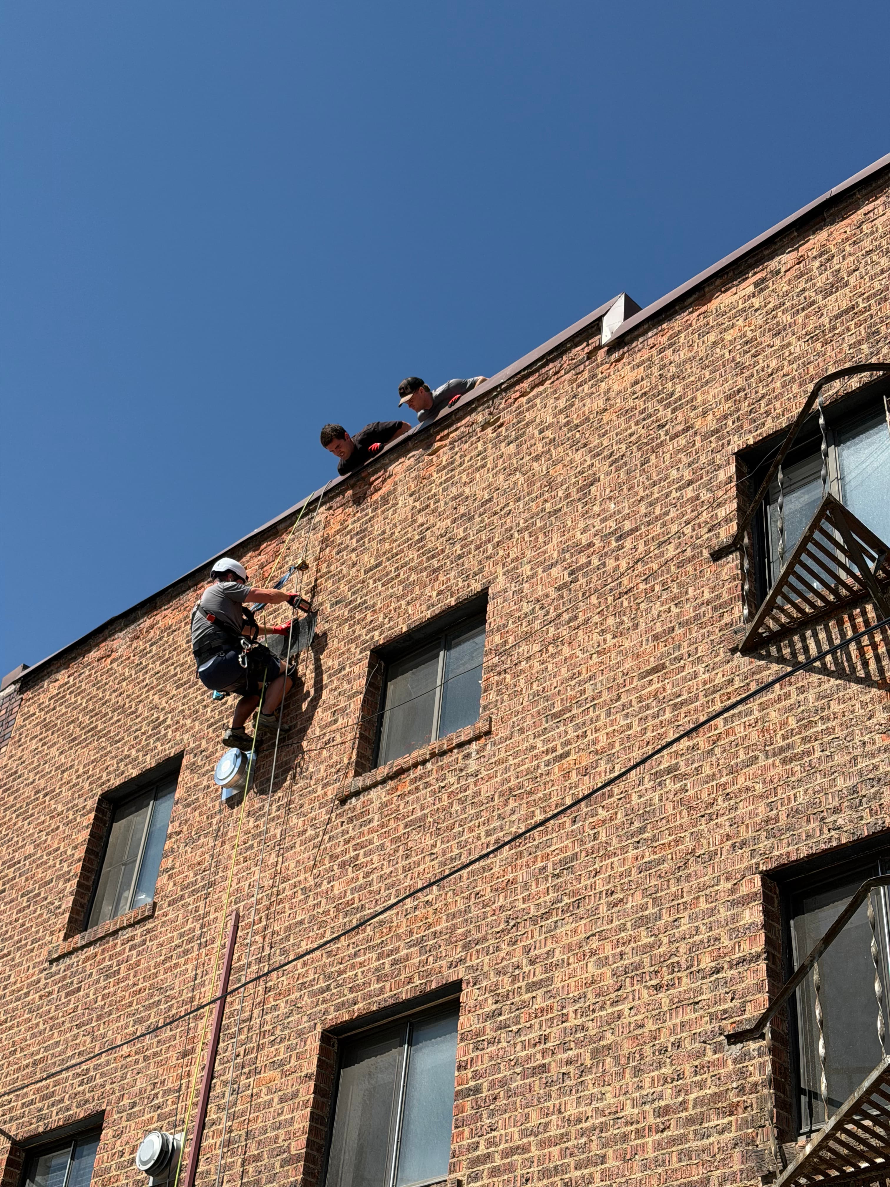 Rope-access technician working on a multi-story brick facade